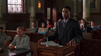 Movie still from “The Brothers” (2001), directed by Gary Hardwick – A man is speaking at a podium in front of a group of people; Medium shot, Low angle