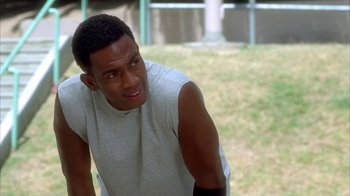 Movie still from “The Brothers” (2001), directed by Gary Hardwick – A man in a white shirt is sitting in a field; Close Up shot, Over the shoulder angle