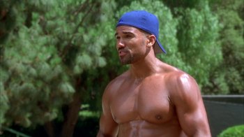 Movie still from “The Brothers” (2001), directed by Gary Hardwick – A man in a blue hat is standing in the grass; Medium shot, High angle