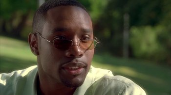 Movie still from “The Brothers” (2001), directed by Gary Hardwick – A person wearing glasses with trees in the background; Close Up shot, Over the shoulder angle
