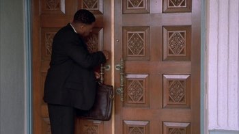 Movie still from “The Brothers” (2001), directed by Gary Hardwick – A man in a black suit is opening a door; Medium shot, High angle