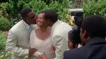 Movie still from “The Brothers” (2001), directed by Gary Hardwick – A man taking a picture of a woman kissing a man on the cheek; Medium shot, High angle