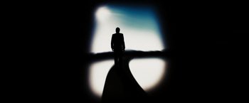 Movie still from “The Brothers Bloom” (2008), directed by Rian Johnson – A man in a suit standing in front of a window; Wide shot, Low angle