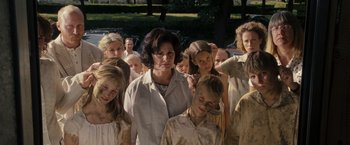 Movie still from “The Brothers Bloom” (2008), directed by Rian Johnson – A group of people standing in a field with trees in the background; Medium shot, Low angle