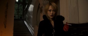 Movie still from “The Brothers Bloom” (2008), directed by Rian Johnson – A woman in a black jacket standing in front of a staircase; Close Up shot, Low angle