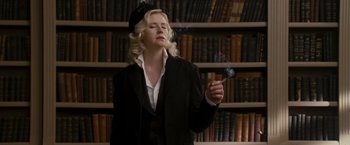 Movie still from “The Brothers Bloom” (2008), directed by Rian Johnson – A woman in a black jacket and a black hat smoking a cigarette; Medium shot, Low angle