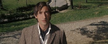 Movie still from “The Brothers Bloom” (2008), directed by Rian Johnson – A man wearing a suit and tie standing in a park; Close Up shot, High angle