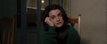 Movie still from “The Brothers Bloom” (2008), directed by Rian Johnson – A woman sitting in a chair with her head resting on her hand; Close Up shot, High angle