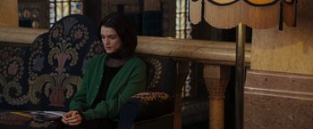 Movie still from “The Brothers Bloom” (2008), directed by Rian Johnson – A woman sitting on a chair in a room; Medium shot, High angle