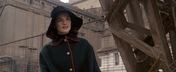 Movie still from “The Brothers Bloom” (2008), directed by Rian Johnson – A woman wearing a black hat and a green coat; Medium shot, Over the shoulder angle