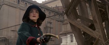 Movie still from “The Brothers Bloom” (2008), directed by Rian Johnson – A woman in a hat and gloves holding a book; Medium shot, Low angle