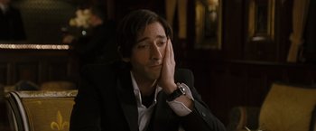 Movie still from “The Brothers Bloom” (2008), directed by Rian Johnson – A man in a black suit is holding his hand up to his face; Close Up shot, High angle