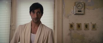 Movie still from “The Brothers Bloom” (2008), directed by Rian Johnson – A man in a white robe standing in a room; Close Up shot, Over the shoulder angle