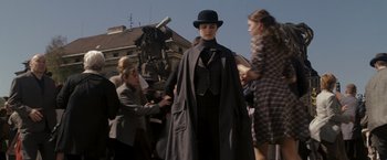 Movie still from “The Brothers Bloom” (2008), directed by Rian Johnson – A woman wearing a black hat and a long black coat; Wide shot, Low angle