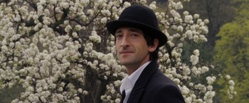 Movie still from “The Brothers Bloom” (2008), directed by Rian Johnson – A man wearing a black hat and a black suit; Close Up shot, Over the shoulder angle