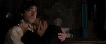 Movie still from “The Brothers Bloom” (2008), directed by Rian Johnson – Two men embracing each other in a dark room; Close Up shot, Low angle