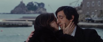Movie still from “The Brothers Bloom” (2008), directed by Rian Johnson – A man and a woman kissing in front of a body of water; Close Up shot, Over the shoulder angle