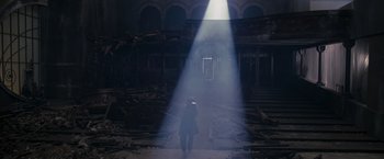 Movie still from “The Brothers Bloom” (2008), directed by Rian Johnson – A person walking in a dark room with a light shining on them; Extreme Wide shot, Low angle