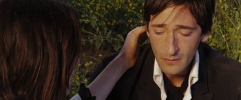 Movie still from “The Brothers Bloom” (2008), directed by Rian Johnson – A woman is putting on a man's ear outside; Close Up shot, High angle