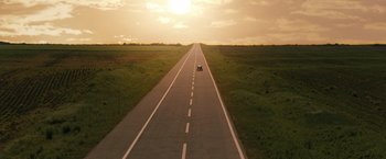 Movie still from “The Brothers Bloom” (2008), directed by Rian Johnson – A car driving down the middle of an empty road; Extreme Wide shot, High angle