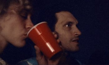 Movie still from “The Brown Bunny” (2003), directed by Vincent Gallo – A man holding a red cup up to his ear; Close Up shot, Low angle