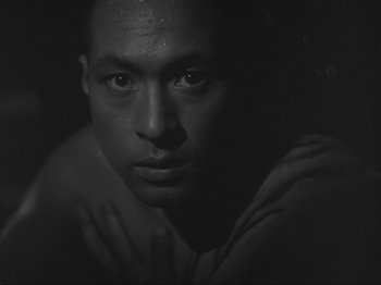 A black and white photo of a man with his hands on his chest