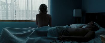 Movie still from “The Burning Plain” (2008), directed by Guillermo Arriaga – A naked woman sitting on a bed looking out a window; Medium shot, Over the shoulder angle
