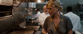 Movie still from “The Burning Plain” (2008), directed by Guillermo Arriaga – A woman standing in front of a man cooking in a kitchen; Close Up shot, Over the shoulder angle