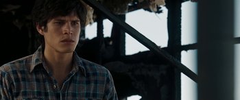 Movie still from “The Burning Plain” (2008), directed by Guillermo Arriaga – A man in a plaid shirt standing in front of a building; Close Up shot, Over the shoulder angle