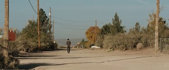 Movie still from “The Burning Plain” (2008), directed by Guillermo Arriaga – A man walking down a dirt road near power lines; Extreme Wide shot, High angle