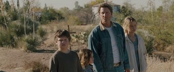 Movie still from “The Burning Plain” (2008), directed by Guillermo Arriaga – A man standing next to two young children in a field; Medium shot, Over the shoulder angle