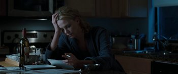 Movie still from “The Burning Plain” (2008), directed by Guillermo Arriaga – A woman sitting at a table looking at a book; Medium shot, High angle