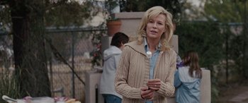 Movie still from “The Burning Plain” (2008), directed by Guillermo Arriaga – A woman holding a cell phone while standing next to a fence; Medium shot, Over the shoulder angle