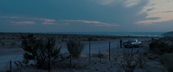 Movie still from “The Burning Plain” (2008), directed by Guillermo Arriaga – A person standing on a dirt road near a fence; Extreme Wide shot, Low angle