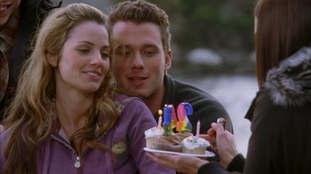 Movie still from “The Butterfly Effect 2” (2006), directed by John R. Leonetti – A man and a woman are holding a cake with candles on it; Close Up shot, Over the shoulder angle