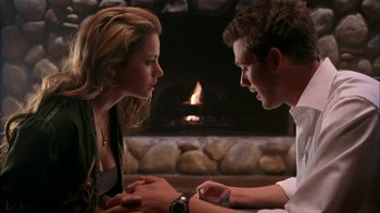 Movie still from “The Butterfly Effect 2” (2006), directed by John R. Leonetti – A man and a woman sitting in front of a fireplace; Medium shot, Over the shoulder angle