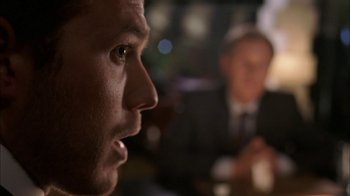 Movie still from “The Butterfly Effect 2” (2006), directed by John R. Leonetti – A man's face as a man in a suit looks on; Close Up shot, Over the shoulder angle