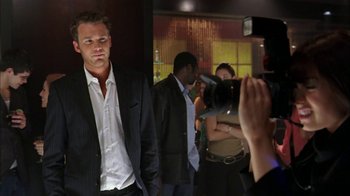 Movie still from “The Butterfly Effect 2” (2006), directed by John R. Leonetti – A group of people taking pictures of a man in a suit; Medium shot, Over the shoulder angle