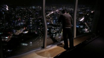Movie still from “The Butterfly Effect 2” (2006), directed by John R. Leonetti – A man looking out a window at a city at night; Wide shot, High angle