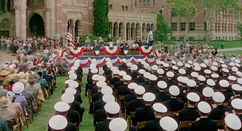 Movie still from “The Caine Mutiny” (1954), directed by Edward Dmytryk – A crowd of people sitting on chairs in front of a building; Extreme Wide shot, High angle