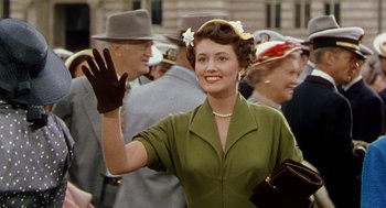 Movie still from “The Caine Mutiny” (1954), directed by Edward Dmytryk – A woman in a green dress waves to the crowd; Medium shot, Over the shoulder angle
