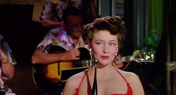 Movie still from “The Caine Mutiny” (1954), directed by Edward Dmytryk – A woman in a red dress holding a wine glass; Close Up shot, Low angle