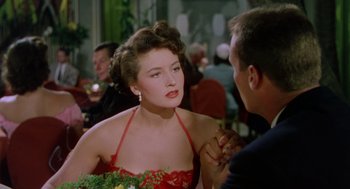 Movie still from “The Caine Mutiny” (1954), directed by Edward Dmytryk – A woman in a red dress talking to a man in a black suit; Close Up shot, Over the shoulder angle