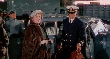 Movie still from “The Caine Mutiny” (1954), directed by Edward Dmytryk – An older woman in a fur coat and a man in a navy uniform; Medium shot, Over the shoulder angle