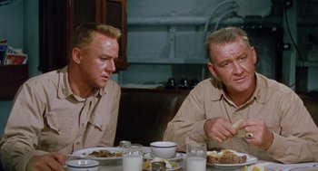 Movie still from “The Caine Mutiny” (1954), directed by Edward Dmytryk – A couple of men sitting at a table eating food; Medium shot, Low angle