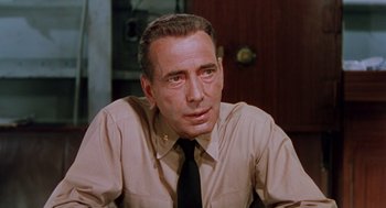 Movie still from “The Caine Mutiny” (1954), directed by Edward Dmytryk – An older man wearing a tan shirt and a black tie; Close Up shot, Low angle