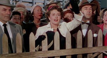 Movie still from “The Caine Mutiny” (1954), directed by Edward Dmytryk – An old photo of a woman waving at a crowd; Medium shot, Low angle