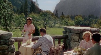 Movie still from “The Caine Mutiny” (1954), directed by Edward Dmytryk – A man and a woman are sitting at a table outside; Wide shot, High angle