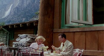 Movie still from “The Caine Mutiny” (1954), directed by Edward Dmytryk – A man and a woman sitting at an outdoor table; Wide shot, High angle