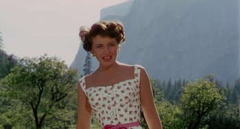 Movie still from “The Caine Mutiny” (1954), directed by Edward Dmytryk – A woman in a floral dress standing in front of a mountain; Medium shot, Low angle